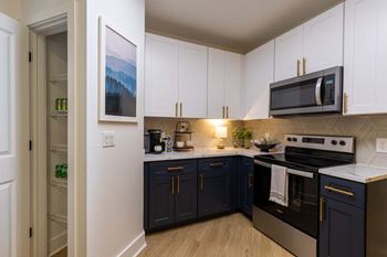 A kitchen with dark blue cabinets and a white microwave above the stove.